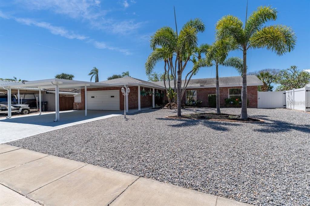A single-story brick house with a gravel front yard, palm trees, and a carport — 6512 KING PALM WAY, APOLLO BEACH, FL