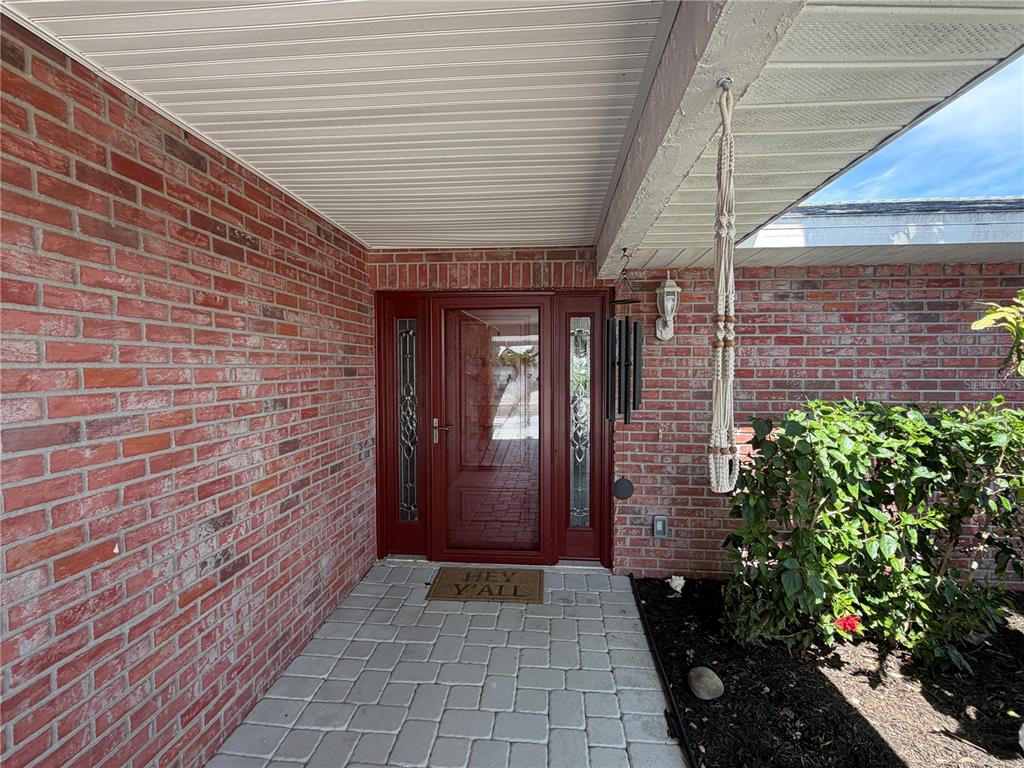 A brick-walled entryway features a red front door with sidelights and a paved walkway — 6512 KING PALM WAY, APOLLO BEACH, FL