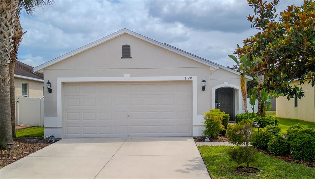 A single-story house with a beige stucco exterior, a two-car garage, and a front entrance — 7120 FOREST MERE DRIVE, RIVERVIEW, FL