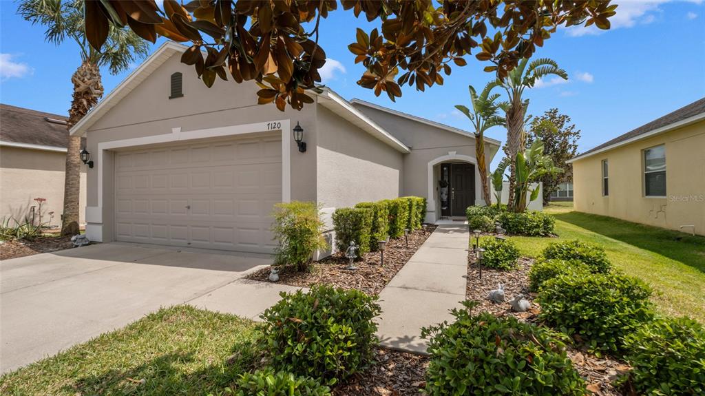 A single-story house with a beige stucco exterior, a two-car garage, and a landscaped walkway — 7120 FOREST MERE DRIVE, RIVERVIEW, FL