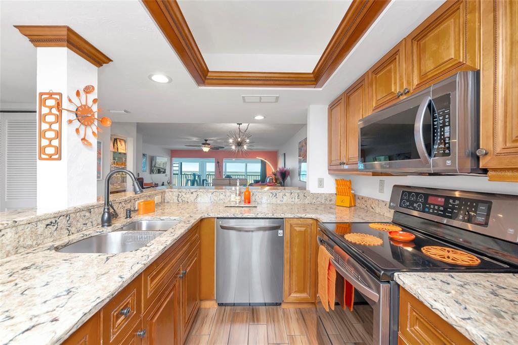 A kitchen features wood cabinets, granite countertops, stainless steel appliances, and an open-concept layout — 910 GOLDEN BEACH BOULEVARD UNIT 202, VENICE, FL