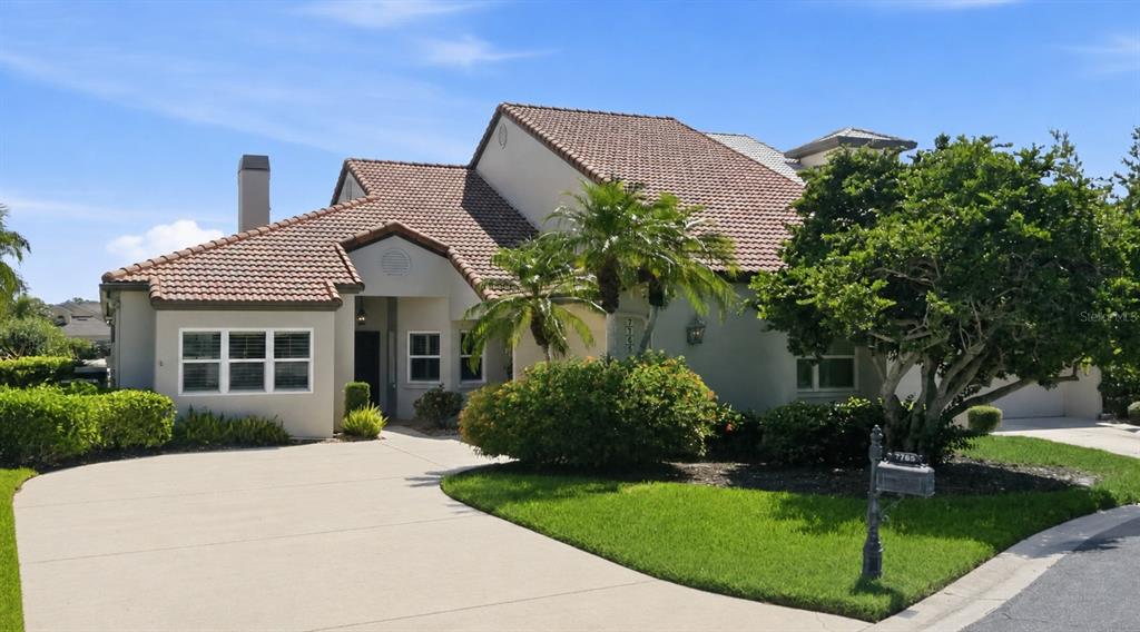 A single-story house with a tiled roof, beige stucco exterior, and a concrete driveway — 7765 CALLE FACIL, SARASOTA, FL