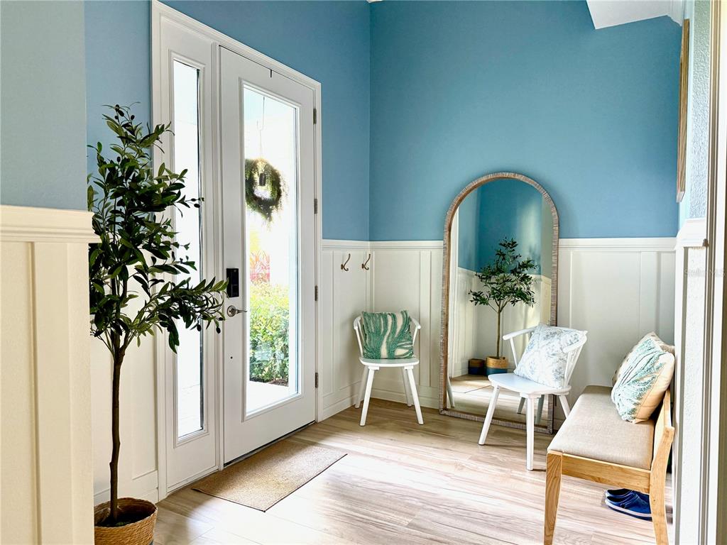 An entryway features blue walls, white wainscoting, a large arched mirror, and a wooden bench — 319 SHORE CRAB WAY, APOLLO BEACH, FL