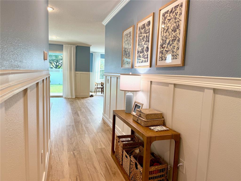 A hallway with board and batten wainscoting leads to a room with a sliding door — 319 SHORE CRAB WAY, APOLLO BEACH, FL