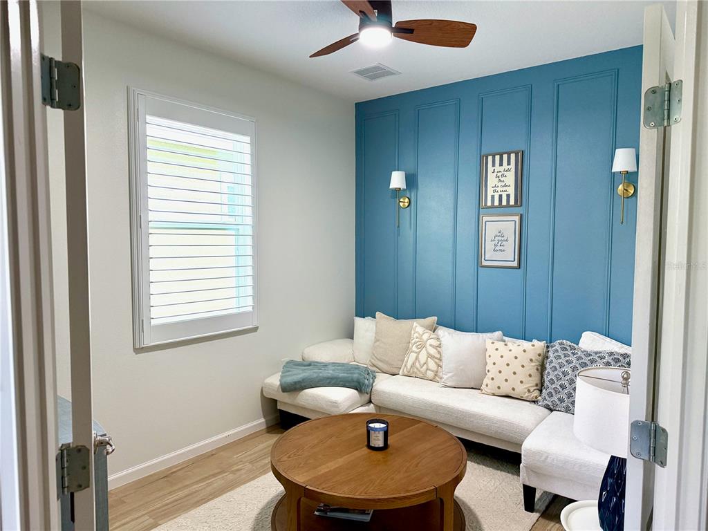 A living room features a blue paneled accent wall, white sectional sofa, and round coffee table — 319 SHORE CRAB WAY, APOLLO BEACH, FL