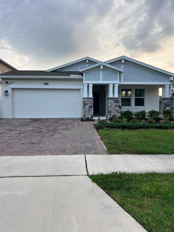 A single-story house with a two-car garage, stone-accented columns, and a paved driveway — 3063 PARK VALE ROAD, ST CLOUD, FL