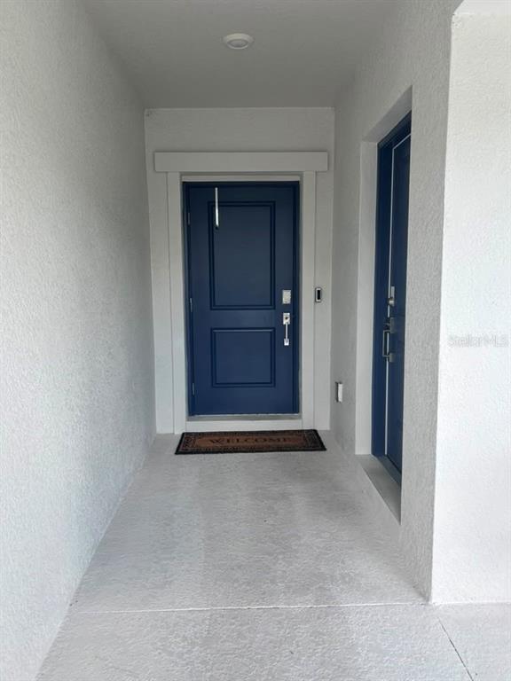 A covered entryway features a blue front door with a welcome mat on concrete flooring — 3063 PARK VALE ROAD, ST CLOUD, FL