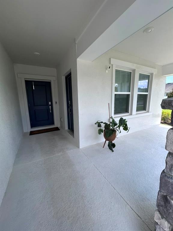A covered front porch features a dark blue door, white walls, and a potted plant — 3063 PARK VALE ROAD, ST CLOUD, FL