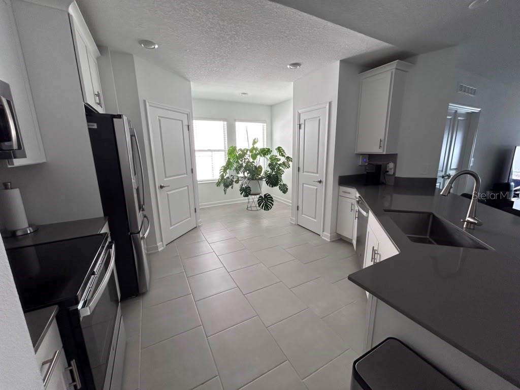 A kitchen with gray countertops, white cabinets, stainless steel appliances, and a large potted plant — 3063 PARK VALE ROAD, ST CLOUD, FL