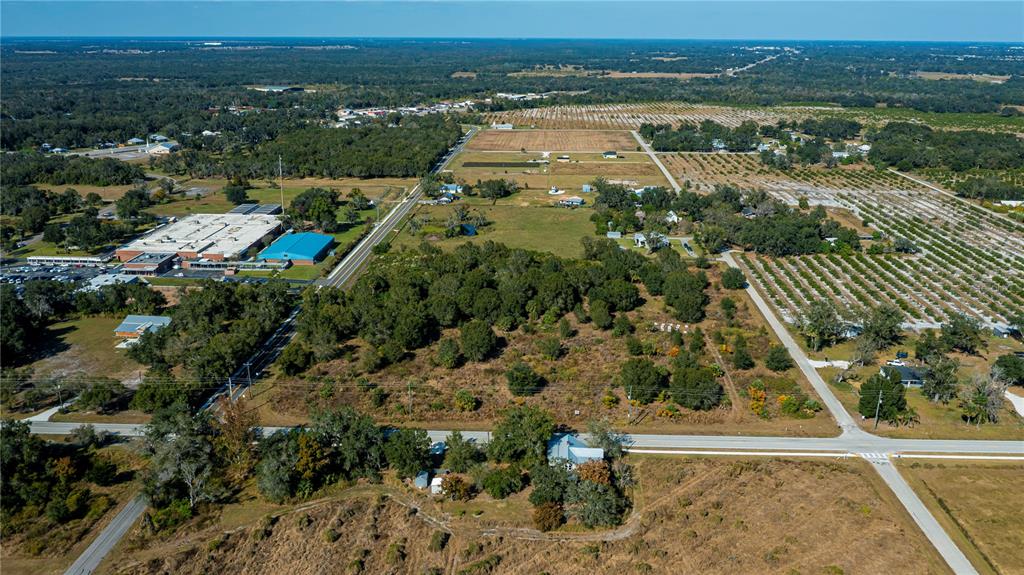An aerial view shows a rural landscape with a large building, fields, and scattered houses — SW CO RD 760A, ARCADIA, FL