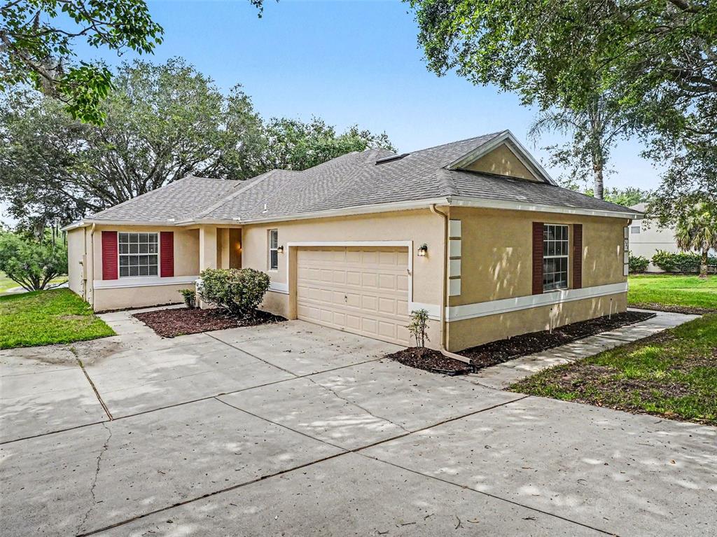 A single-story house with a beige stucco exterior, a two-car garage, and red window shutters — 526 AZALEA BLOOM DRIVE, APOPKA, FL
