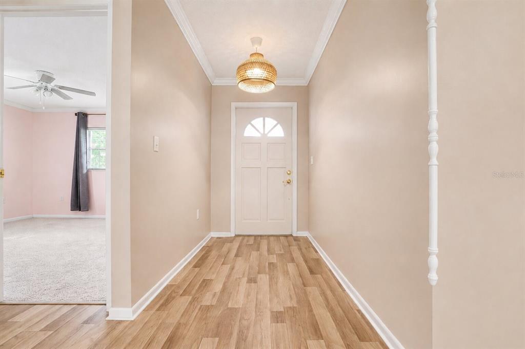 A bright entryway features light-colored walls, wood-look flooring, and a central woven pendant light — 510 PALMER CIRCLE, PALM HARBOR, FL
