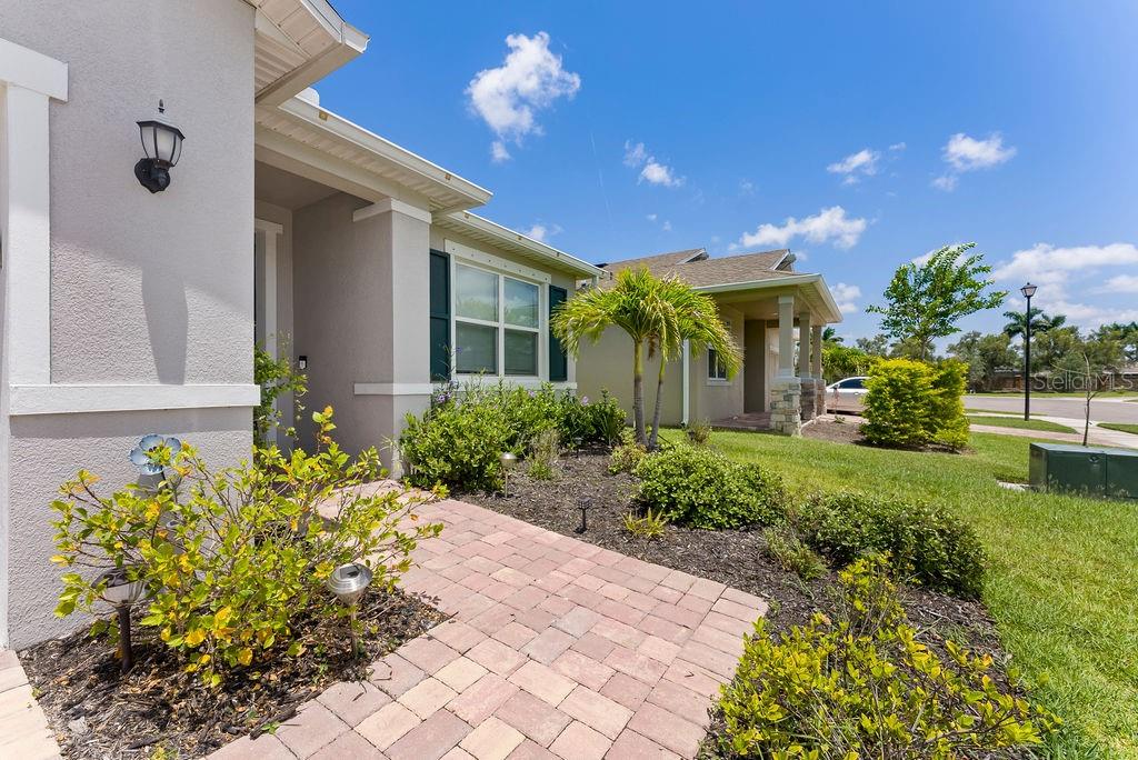 A paved walkway leads to the entrance of a house with a landscaped front yard — 7322 34TH COURT E, SARASOTA, FL