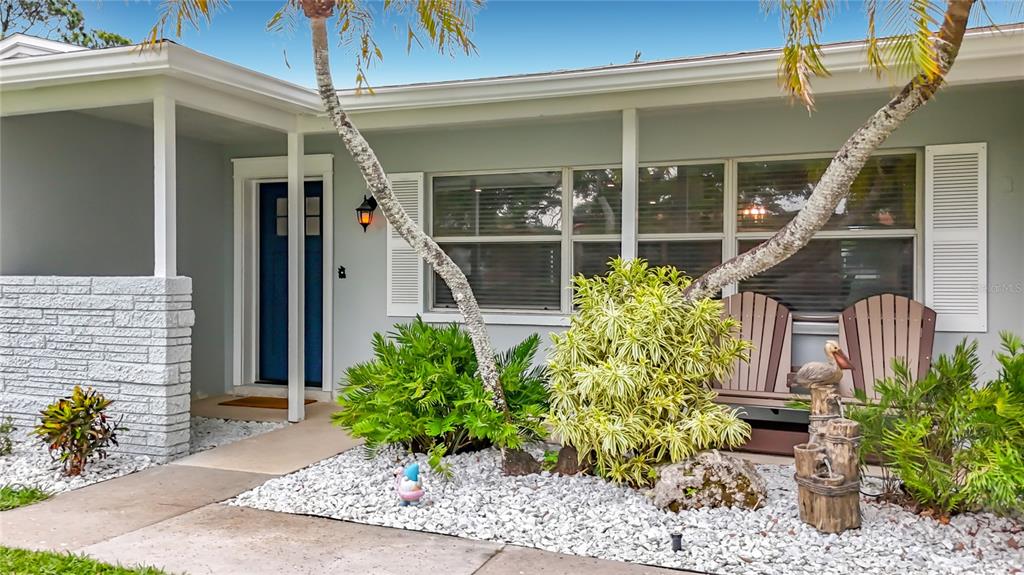 The exterior of a light-colored house features a blue front door and landscaping with rocks — 508 SHORE DRIVE, LARGO, FL