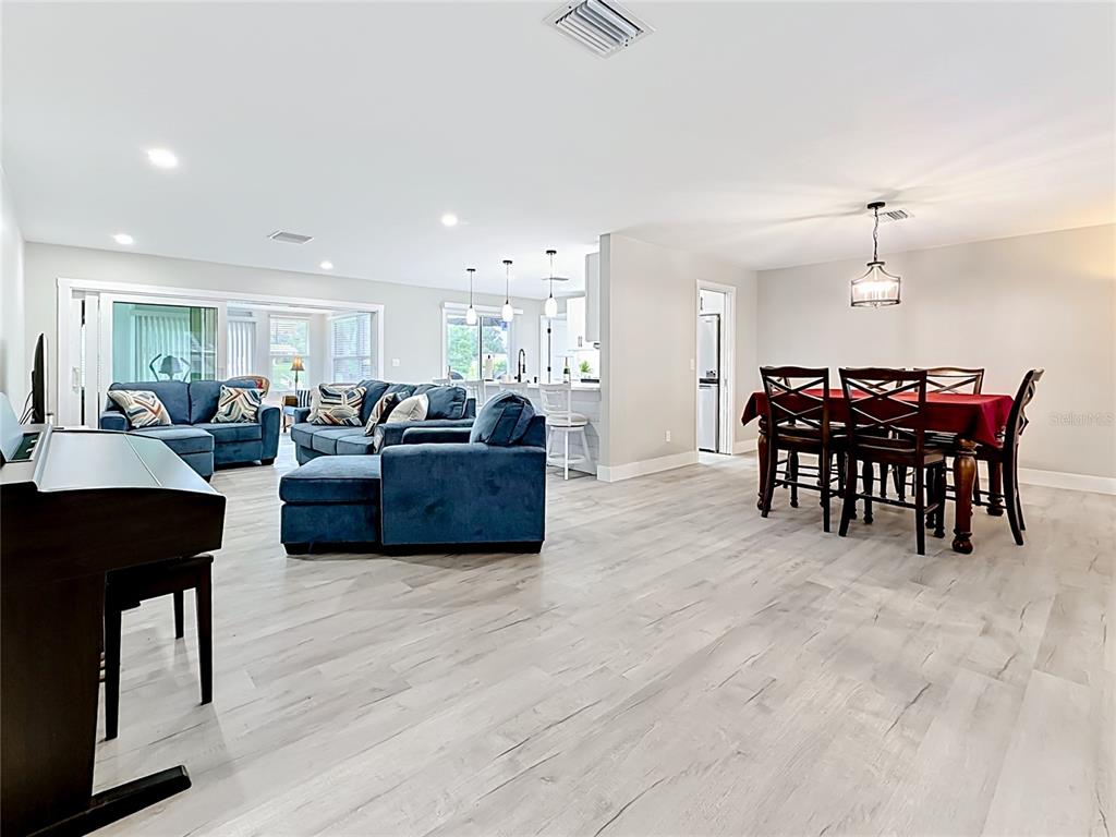 An open-concept living and dining area features light wood-look flooring and blue sectional seating — 508 SHORE DRIVE, LARGO, FL
