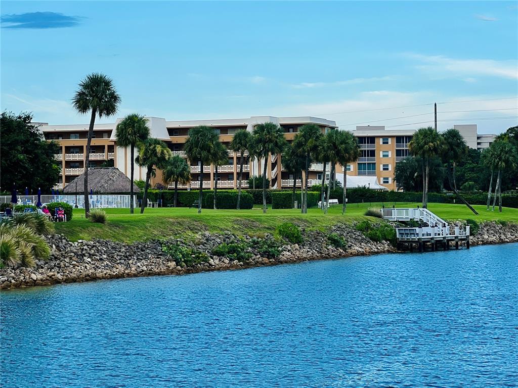 A waterfront view of a multi-story apartment building with palm trees and a private dock — 304 GOLFVIEW ROAD UNIT PH, NORTH PALM BEACH, FL