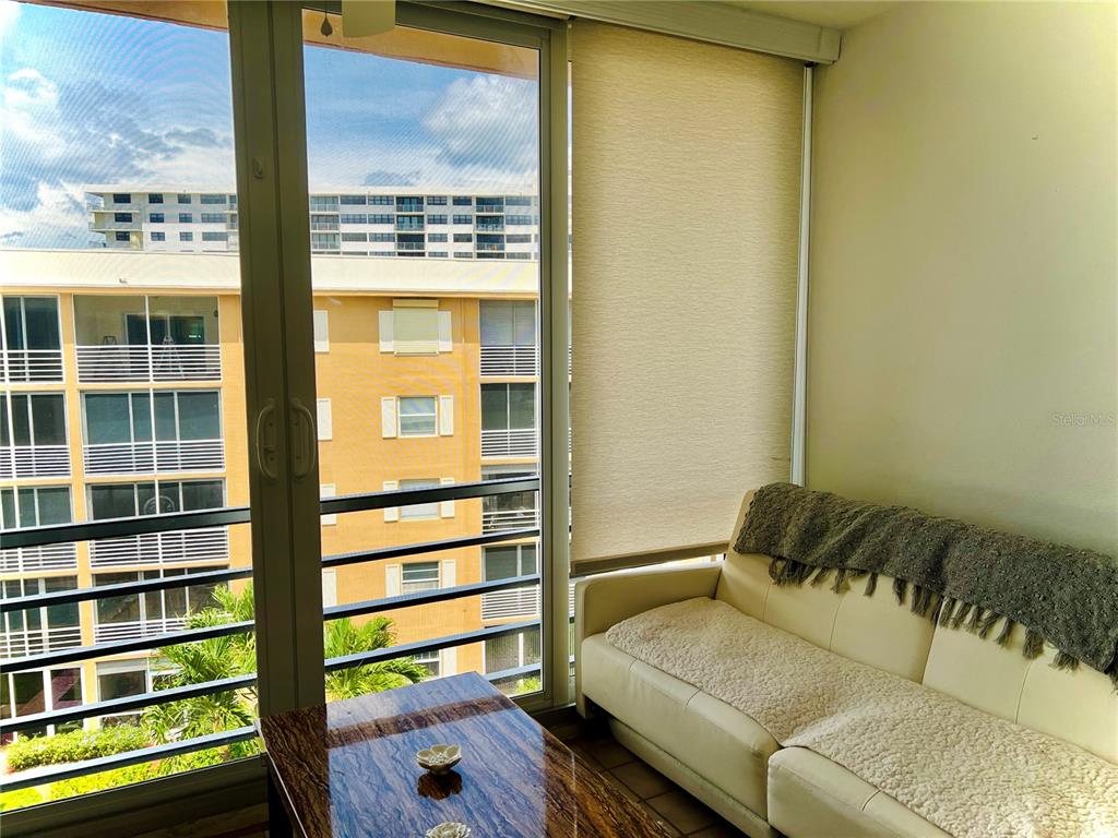 A white sofa sits next to a sliding glass door overlooking a neighboring apartment building — 304 GOLFVIEW ROAD UNIT PH, NORTH PALM BEACH, FL