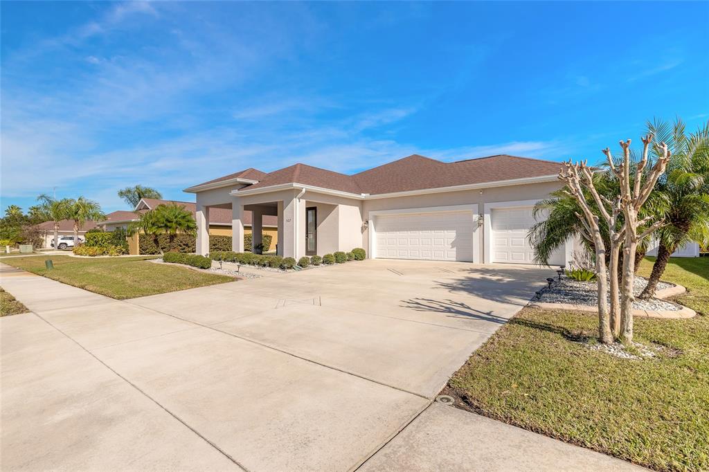 A single-story house with a concrete driveway, a three-car garage, and a landscaped front yard — 527 LUNA BELLA LANE, NEW SMYRNA BEACH, FL