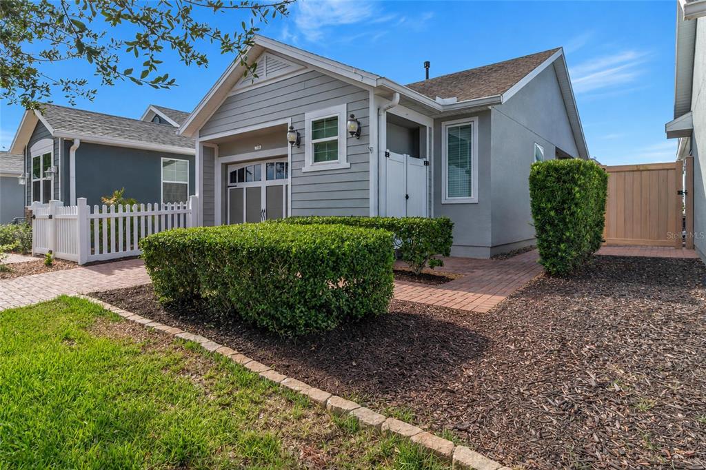 A gray house with a brick walkway, white picket fence, and manicured hedges in front — 78 BAYOU BEND ROAD, GROVELAND, FL
