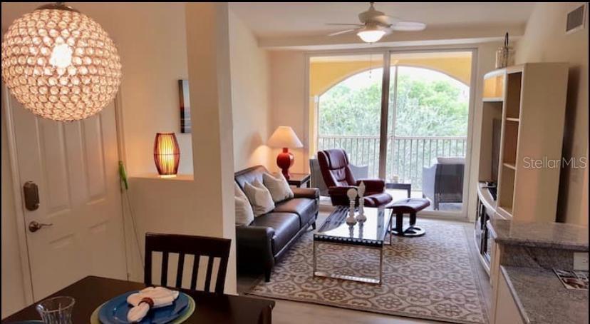A living room with a leather sofa, armchair, glass coffee table, and a balcony view — 4105 RESIDENCE DRIVE UNIT 717, FORT MYERS, FL