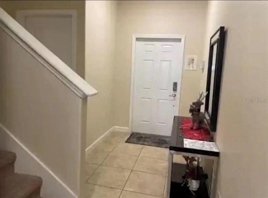 An entryway features tiled flooring, a staircase with carpeted steps, and a white front door — 2935 BANANA PALM DRIVE, KISSIMMEE, FL