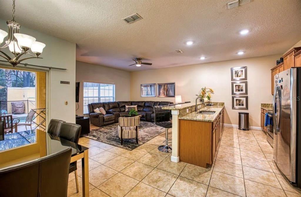 An open-concept kitchen and living area with tile floors, granite countertops, and a sectional sofa — 2935 BANANA PALM DRIVE, KISSIMMEE, FL