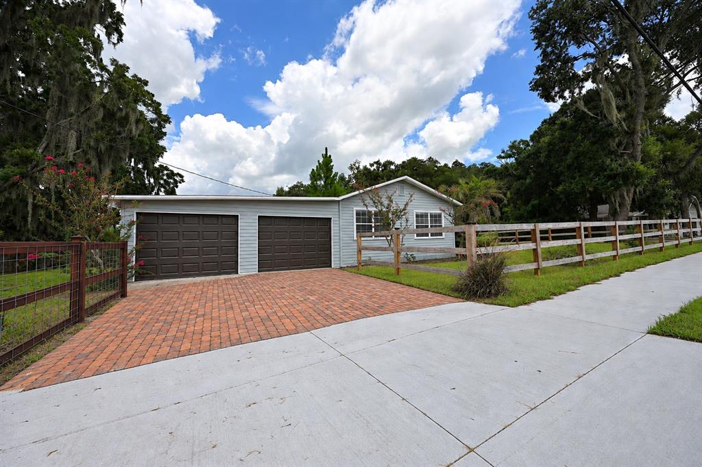A light blue house with a two-car garage and a brick driveway behind a fence — 3958 2ND STREET NW, LAKELAND, FL
