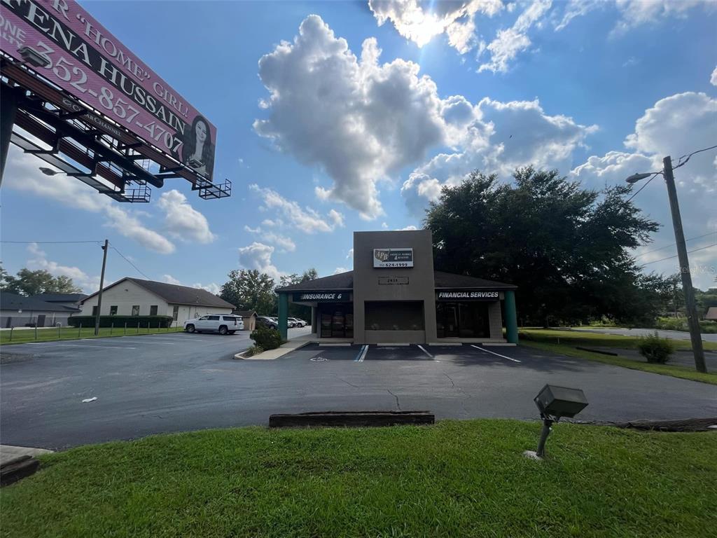 A commercial building with a parking lot and a large billboard stands under a cloudy sky — 2935 SE 58TH AVENUE, OCALA, FL