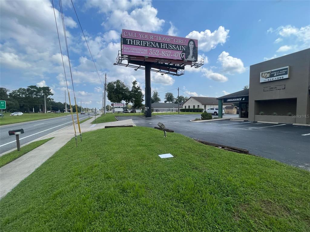 A billboard for a real estate agent stands above a parking lot and grassy area — 2935 SE 58TH AVENUE, OCALA, FL