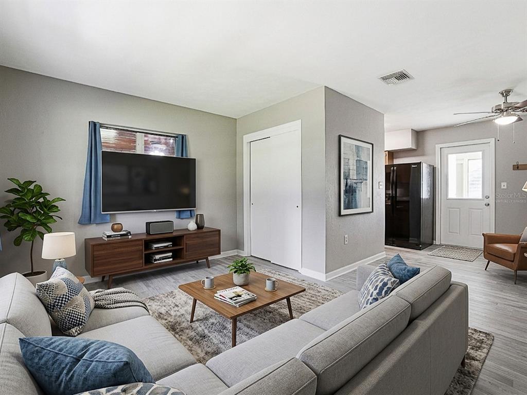 A living room with a sectional sofa, television, media console, and light wood flooring — 2014 HELMS AVENUE, LEESBURG, FL