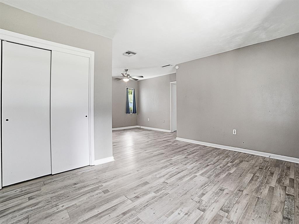 An interior view of a room with gray walls, white trim, and light wood-look flooring — 2014 HELMS AVENUE, LEESBURG, FL