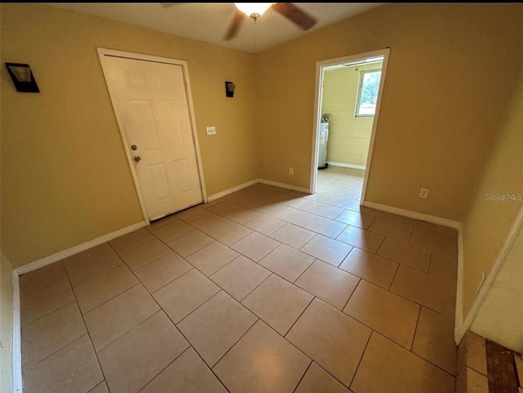 An interior room with tan walls, tiled flooring, a ceiling fan, and a doorway — 116 JUPITER CIRCLE, ORLANDO, FL