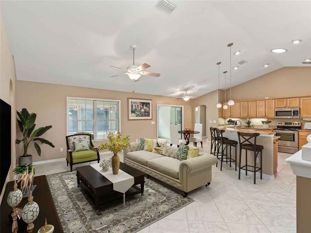 An open-concept living room and kitchen featuring a beige sofa, area rug, and breakfast bar — 17879 SE 125TH CIRCLE, SUMMERFIELD, FL