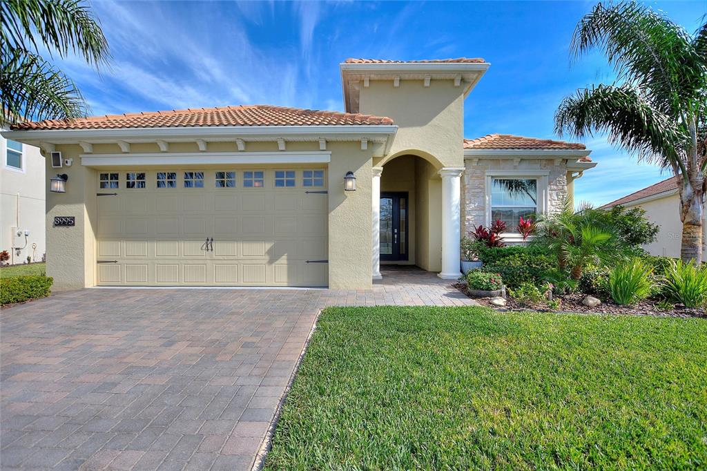 A single-story house with a beige stucco exterior, a tile roof, and a paved driveway — 8995 ACE LOOP, DAVENPORT, FL