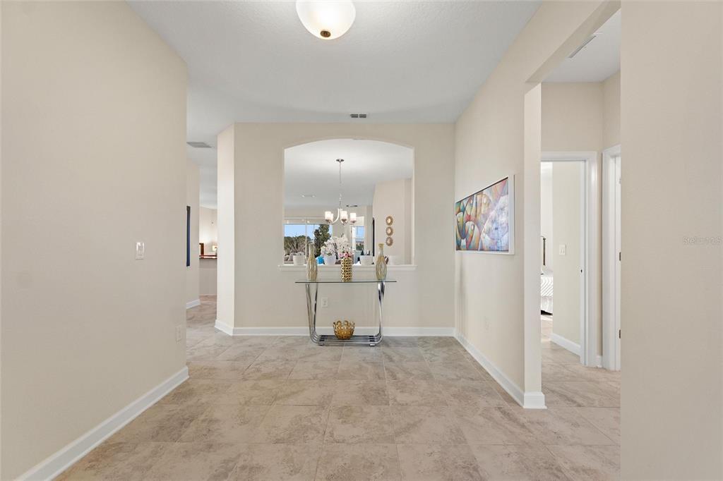A tiled foyer features a glass console table and an arched opening to a living area — 8995 ACE LOOP, DAVENPORT, FL