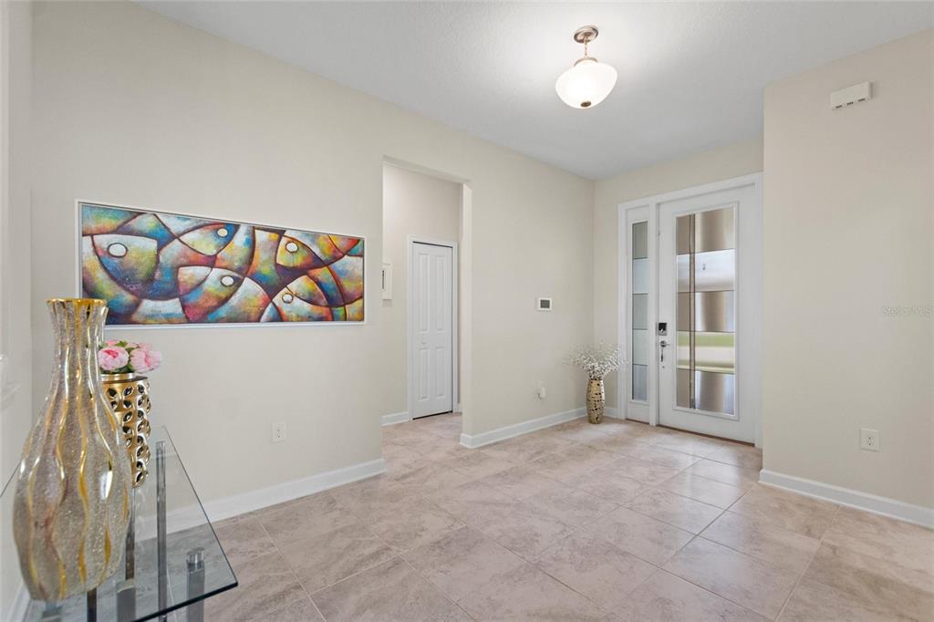 A bright entryway features tile flooring, a glass-paneled front door, and colorful fish wall art — 8995 ACE LOOP, DAVENPORT, FL