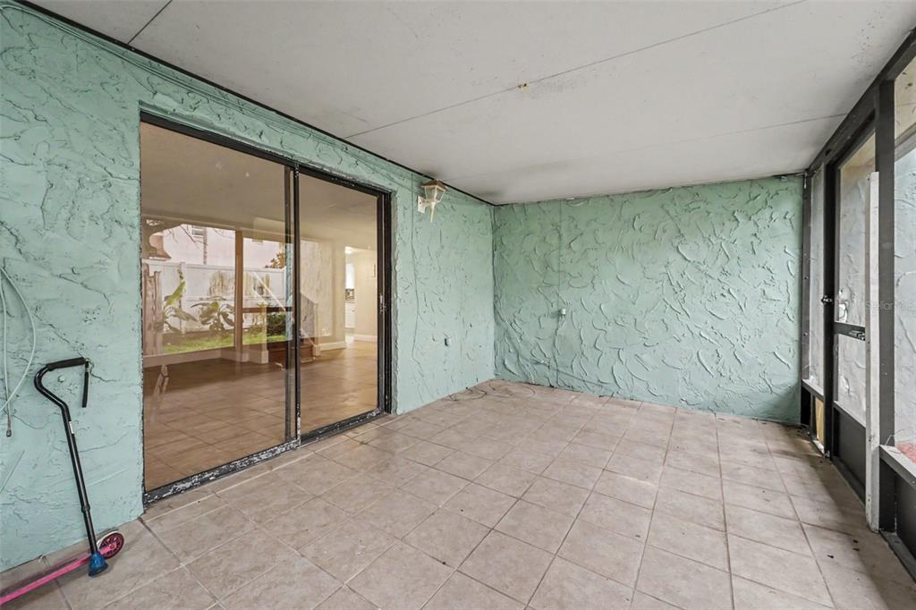 A covered patio with light green textured walls, tiled flooring, and a sliding glass door — 12310 TOUCHTON DRIVE UNIT 43, TAMPA, FL