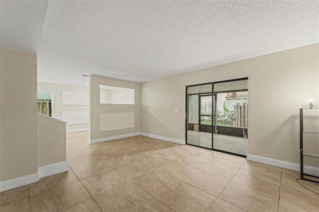 An empty room with light-colored tile flooring and wooden stairs leading to an upper level — 12310 TOUCHTON DRIVE UNIT 43, TAMPA, FL