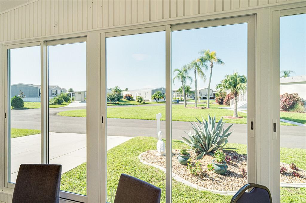 A view through sliding glass doors shows a residential street with palm trees and landscaping — 700 FAIRMOUNT DRIVE, NORTH PORT, FL