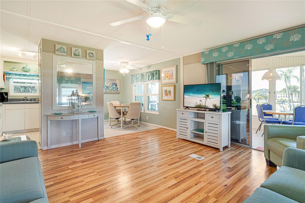 A living room with wood-look flooring, a ceiling fan, and an adjacent dining area — 700 FAIRMOUNT DRIVE, NORTH PORT, FL
