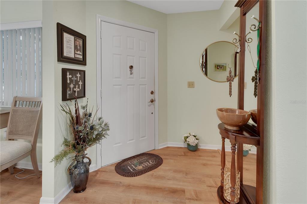 An entryway features a white front door, light wood flooring, and a wooden console table — 904 VILLAGE GREEN ROAD UNIT 3, DELAND, FL