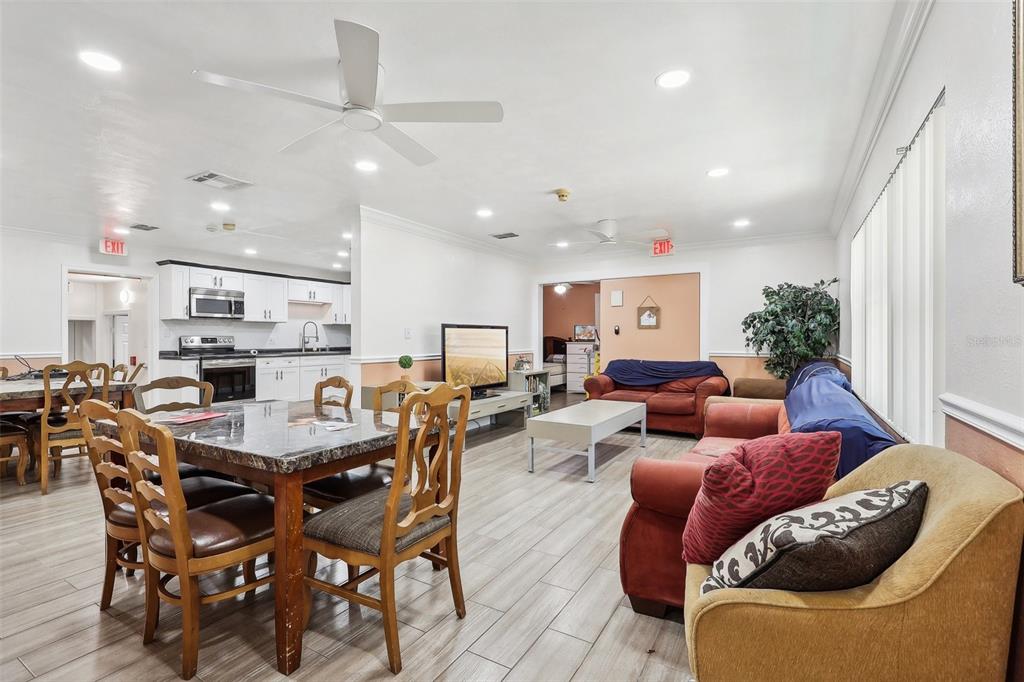 An open-concept living and dining area features light wood-look tile flooring and white cabinetry — 201 ROSEFIELD AVENUE, LEESBURG, FL