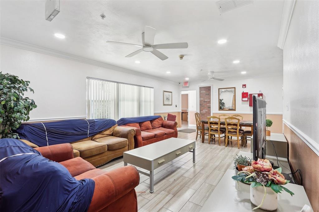 A living and dining area features wood-look tile floors, multiple sofas, and a dining set — 201 ROSEFIELD AVENUE, LEESBURG, FL