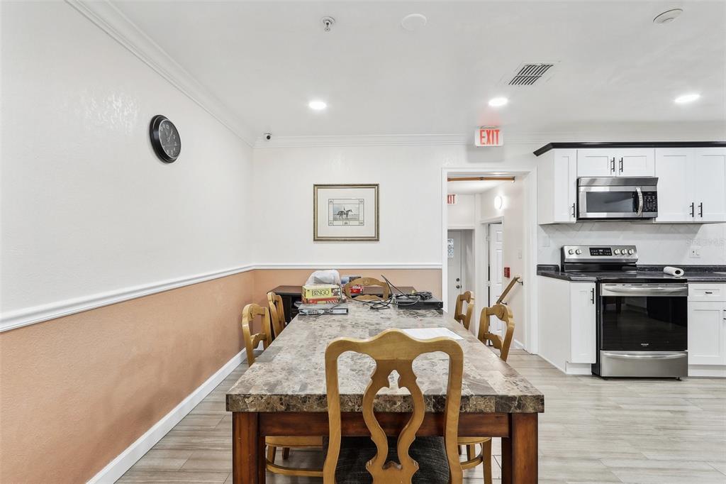 A dining area with a stone-topped table and chairs sits adjacent to a white kitchen — 201 ROSEFIELD AVENUE, LEESBURG, FL