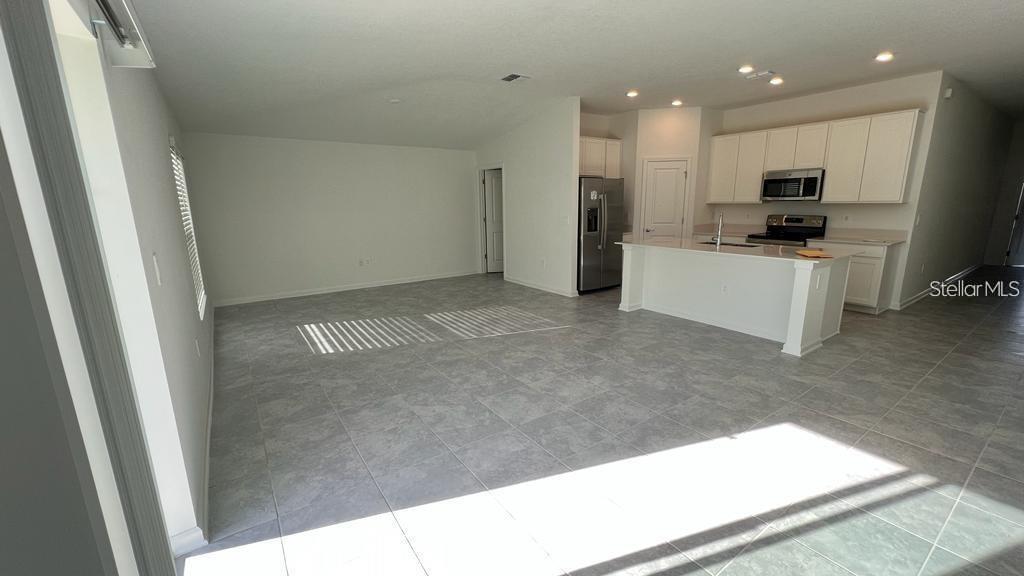 An open-concept kitchen and living area features light gray tile flooring and white cabinetry — 263 BRAVE ROAD, DAVENPORT, FL
