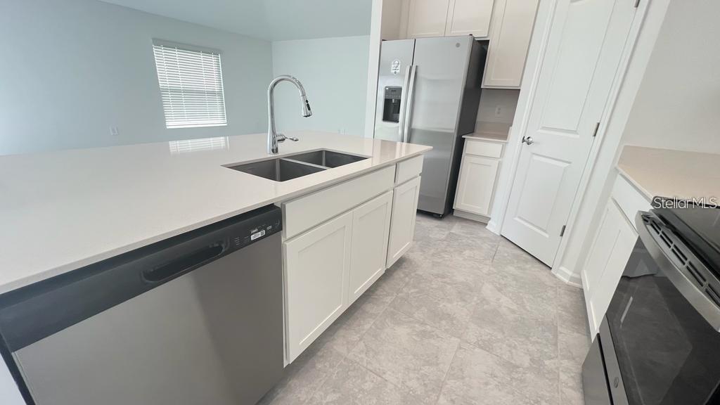A kitchen features white cabinets, stainless steel appliances, and a large island with a sink — 263 BRAVE ROAD, DAVENPORT, FL