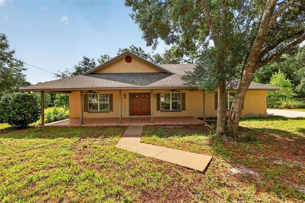 A single-story house with a covered porch, tan siding, and a concrete walkway — 37130 COUNTY ROAD 439, EUSTIS, FL