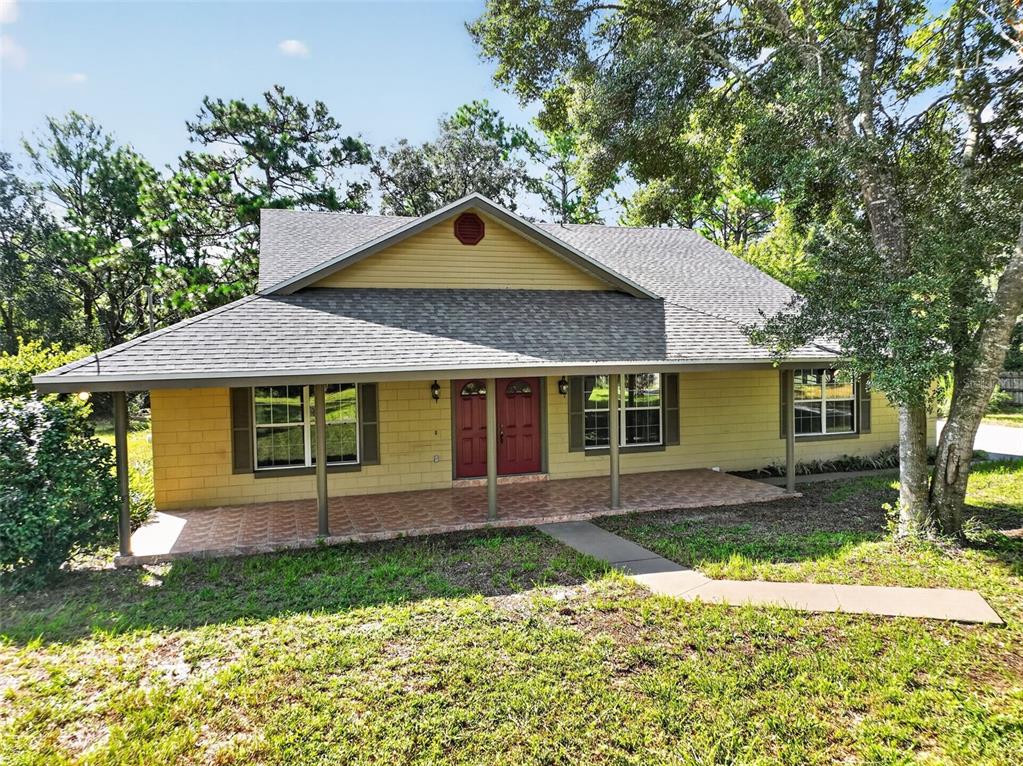 A yellow house with a covered front porch, red double doors, and a gray roof — 37130 COUNTY ROAD 439, EUSTIS, FL
