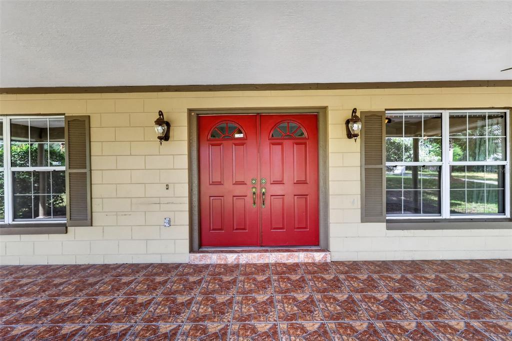 A front porch features a red double door, tiled flooring, and two windows with shutters — 37130 COUNTY ROAD 439, EUSTIS, FL