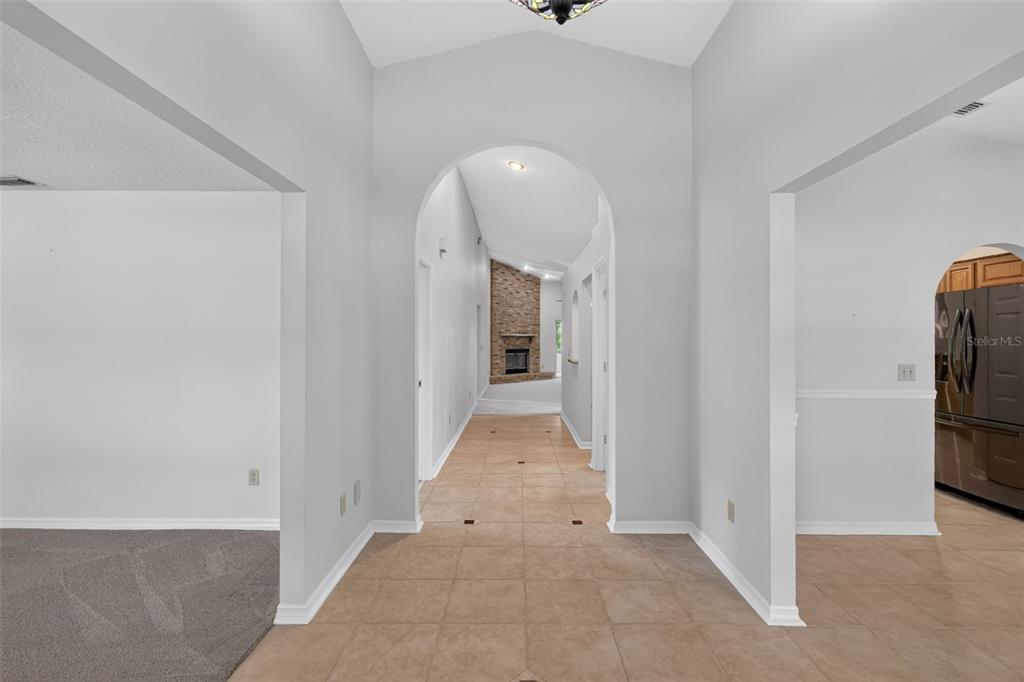 A tiled hallway leads through an arched opening toward a living room with a fireplace — 37130 COUNTY ROAD 439, EUSTIS, FL